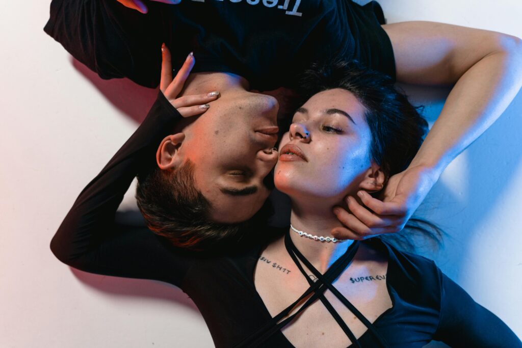 A creative, intimate portrait of a young couple embracing under neon lighting.