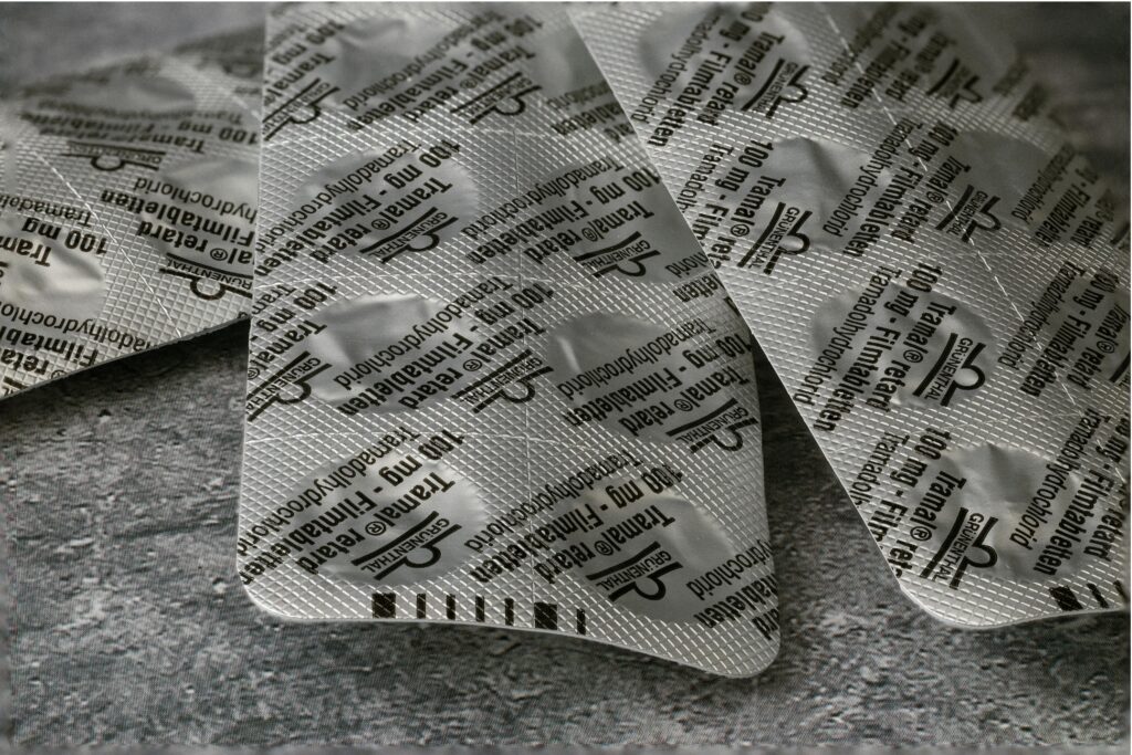 Close-up of Tramadol 100 mg blister pack on a textured concrete surface.