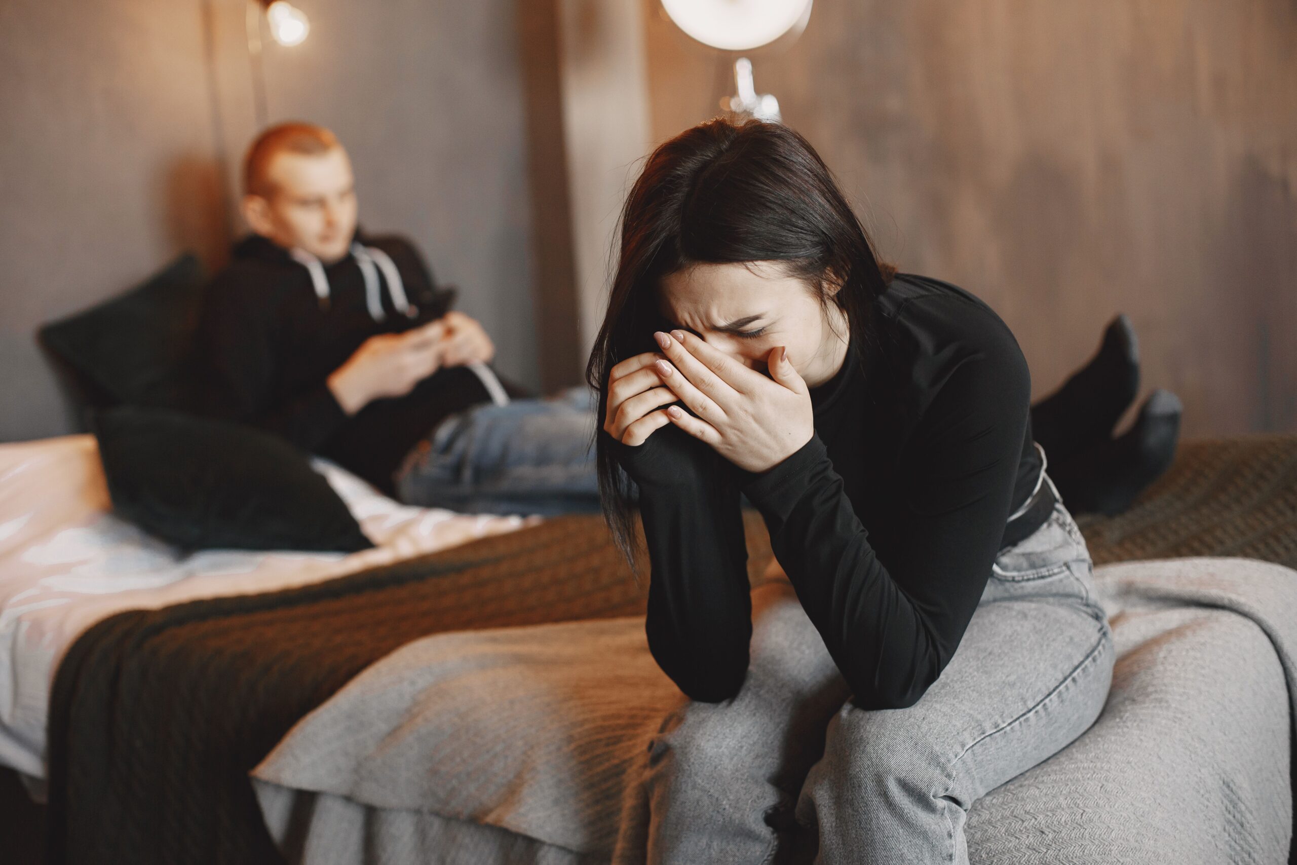A couple experiencing tension and sadness in a modern bedroom setting.