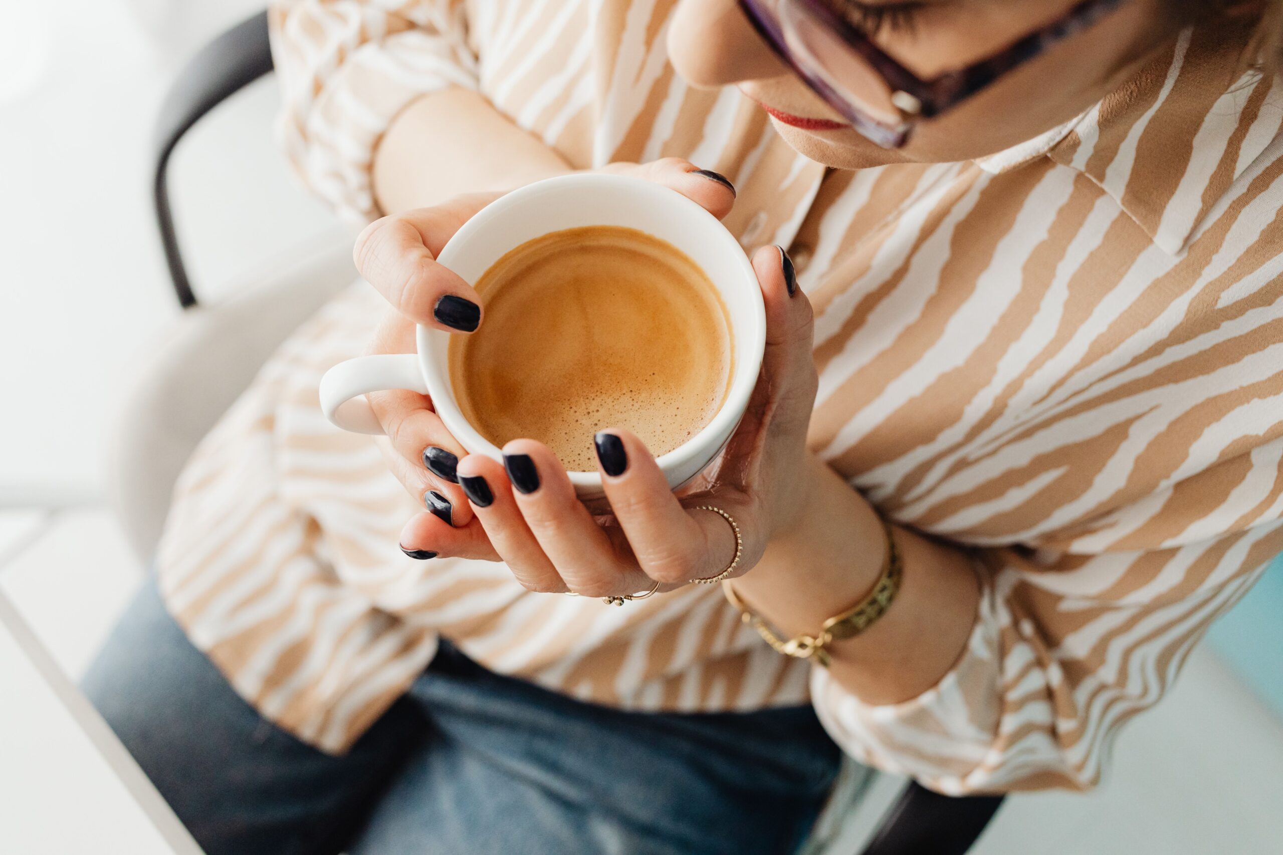 A woman holding a ceramic cup of coffee, enjoying a peaceful moment indoors.